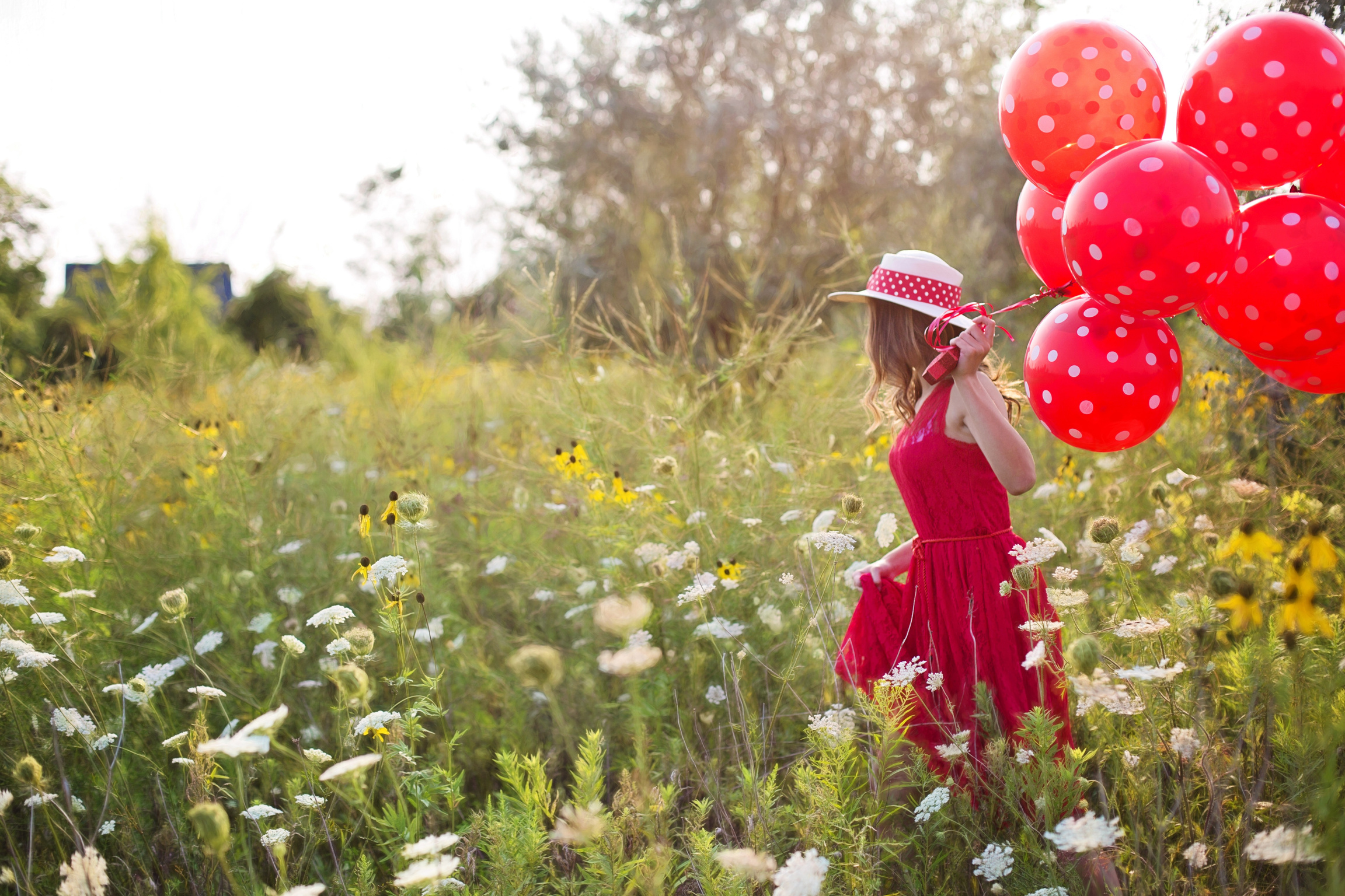 Woman in Red Holding Balloons in a Flower Field